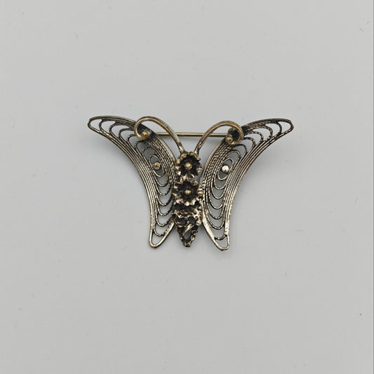 Butterfly-shaped brooch on a light gray background