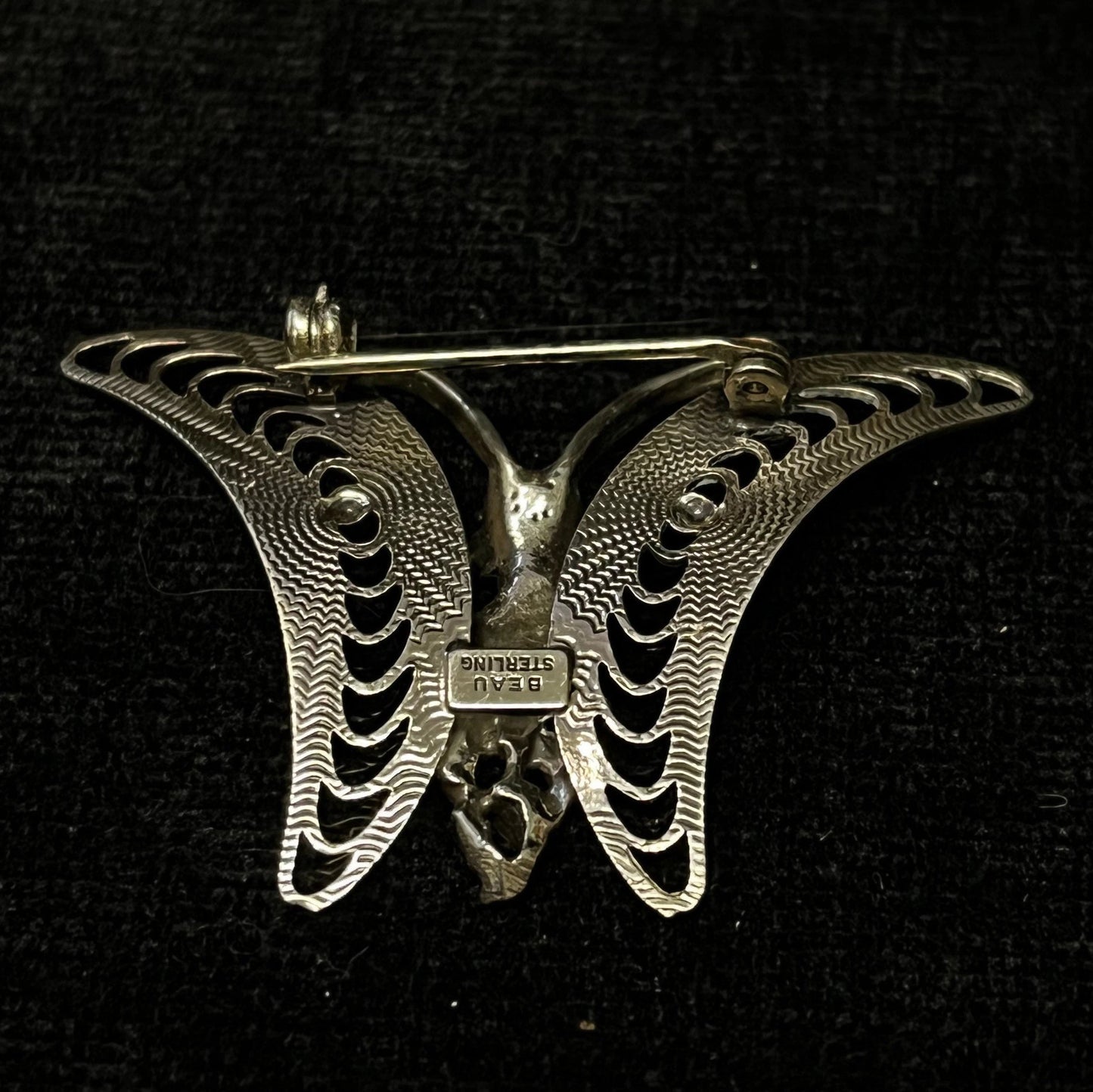 Silver butterfly-shaped brooch on a black background