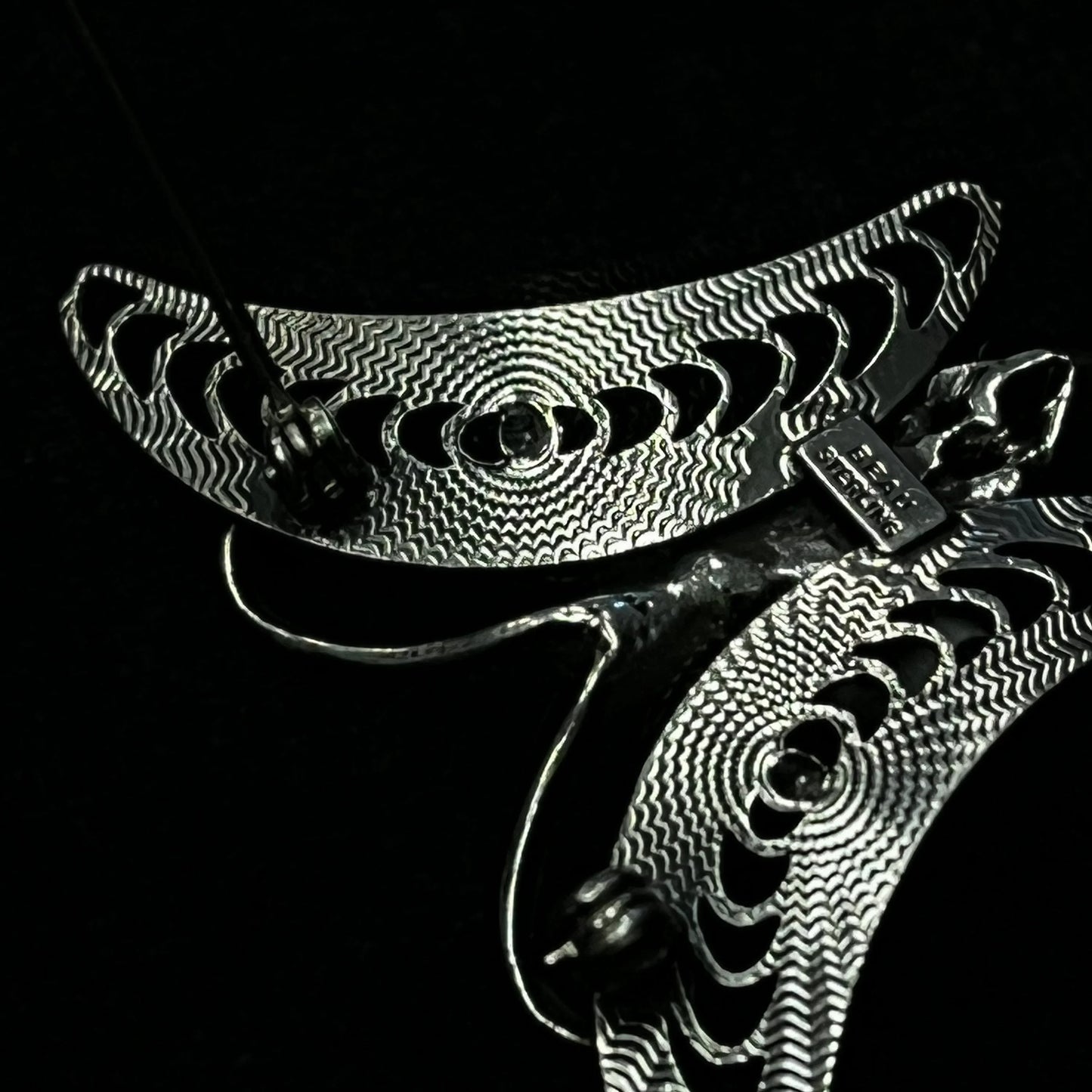 Close-up of back of brooch with intricate patterns on a black background