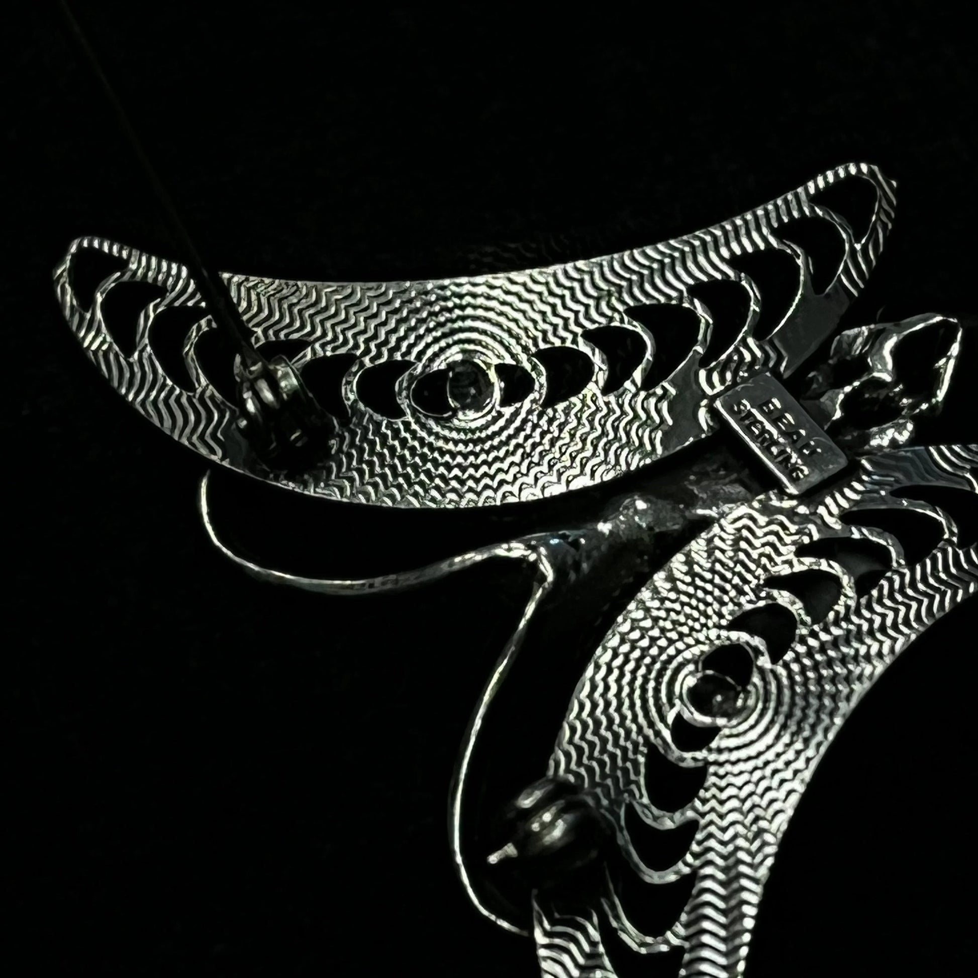 Close-up of back of brooch with intricate patterns on a black background