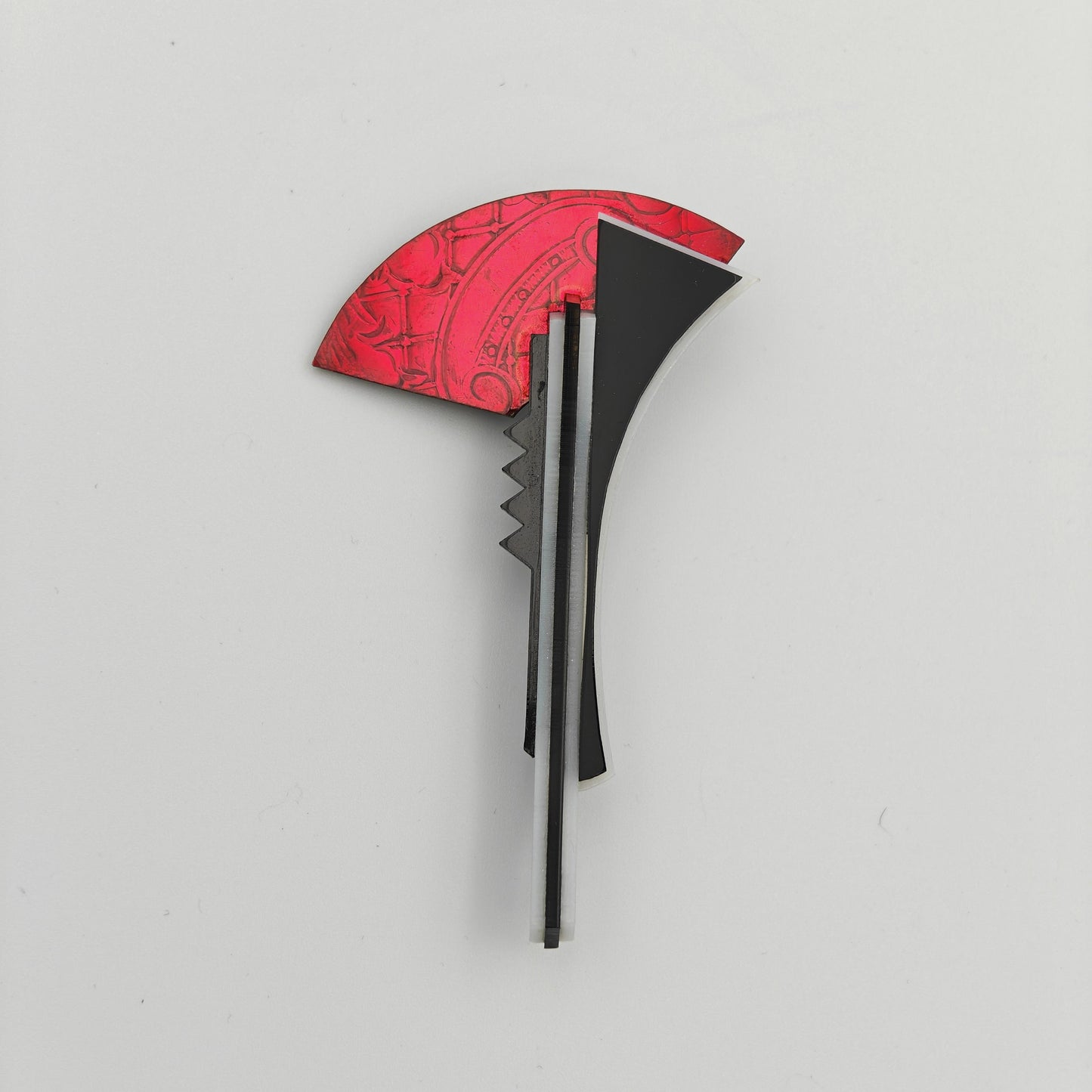 Black and red brooch on a light gray background