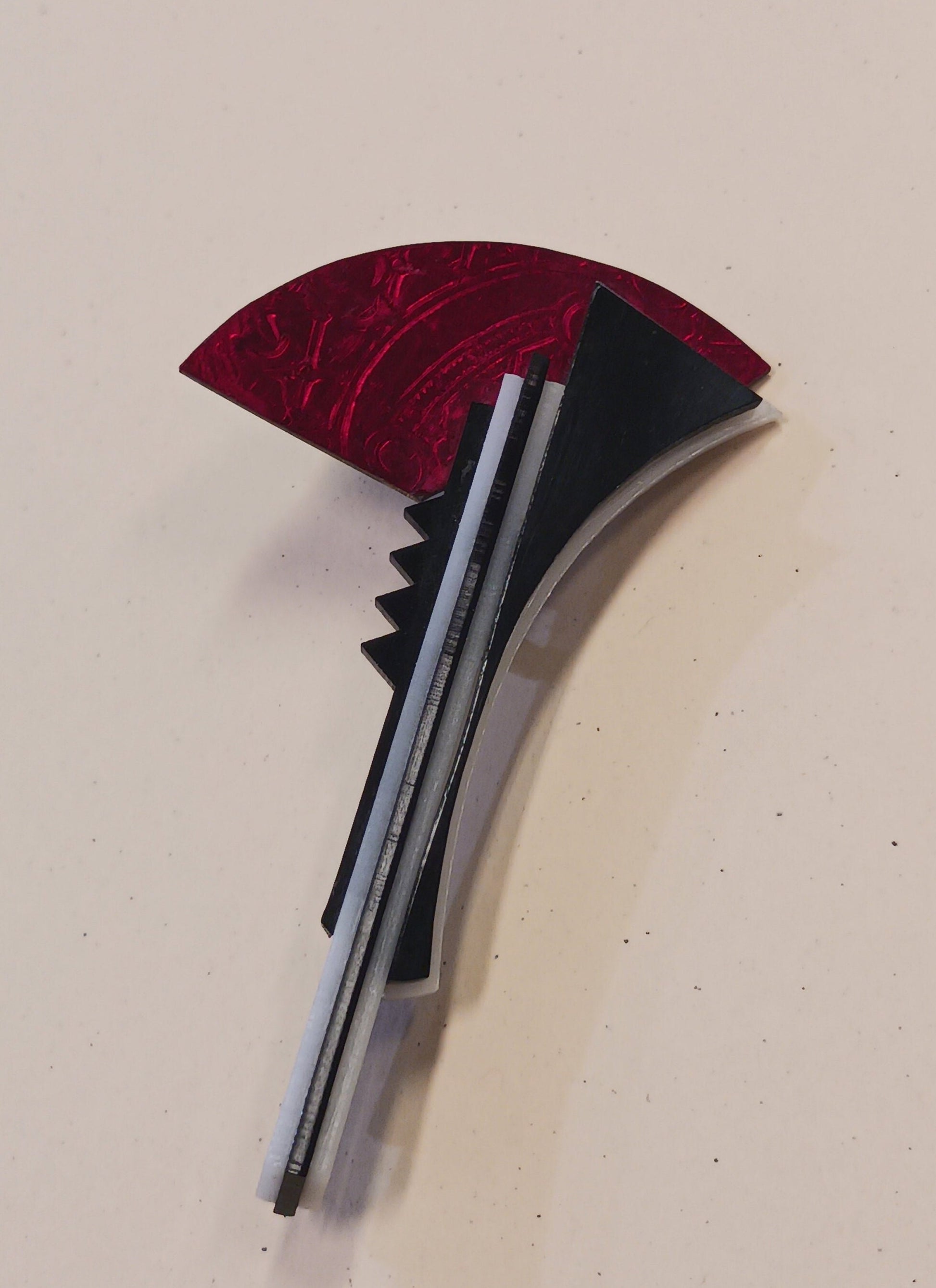 Brooch with red and black design on a light gray background