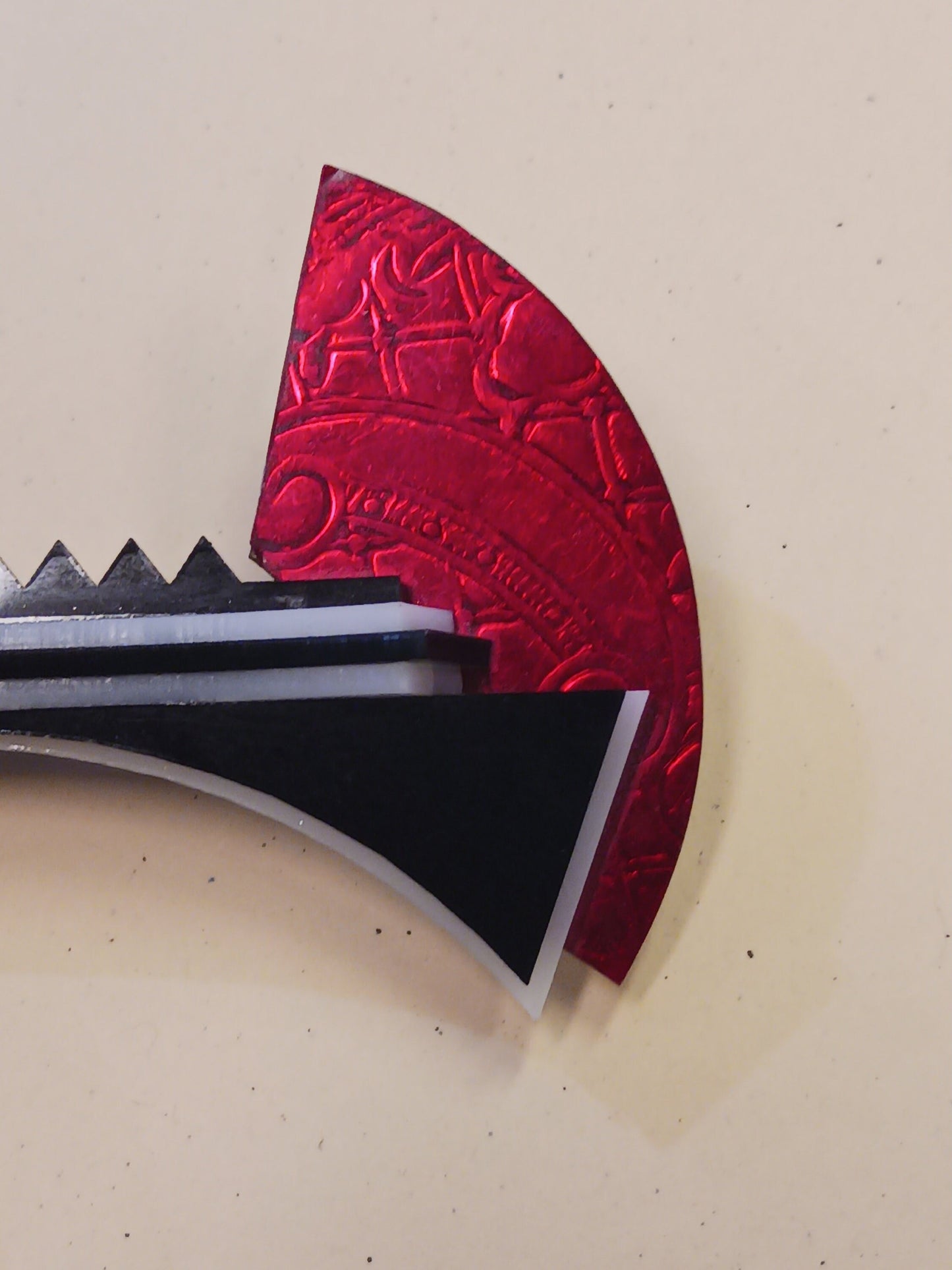 Red and black brooch with a unique design on a beige background