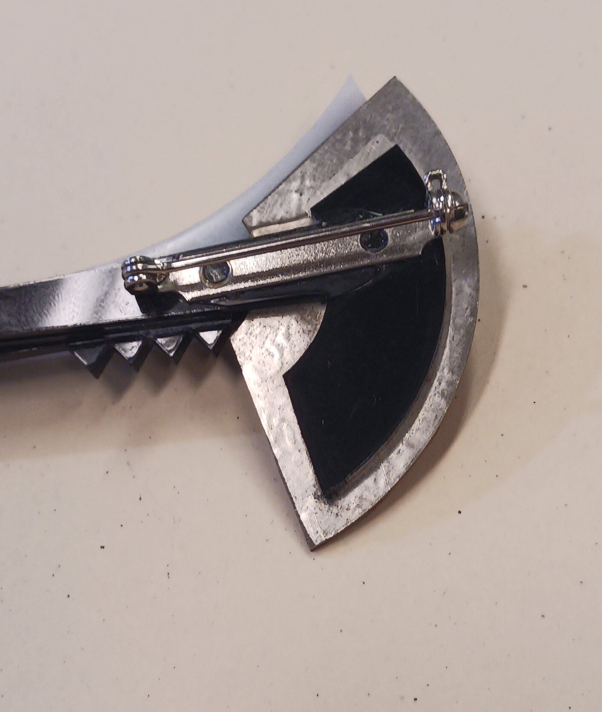 Close up of back of brooch on a light gray background
