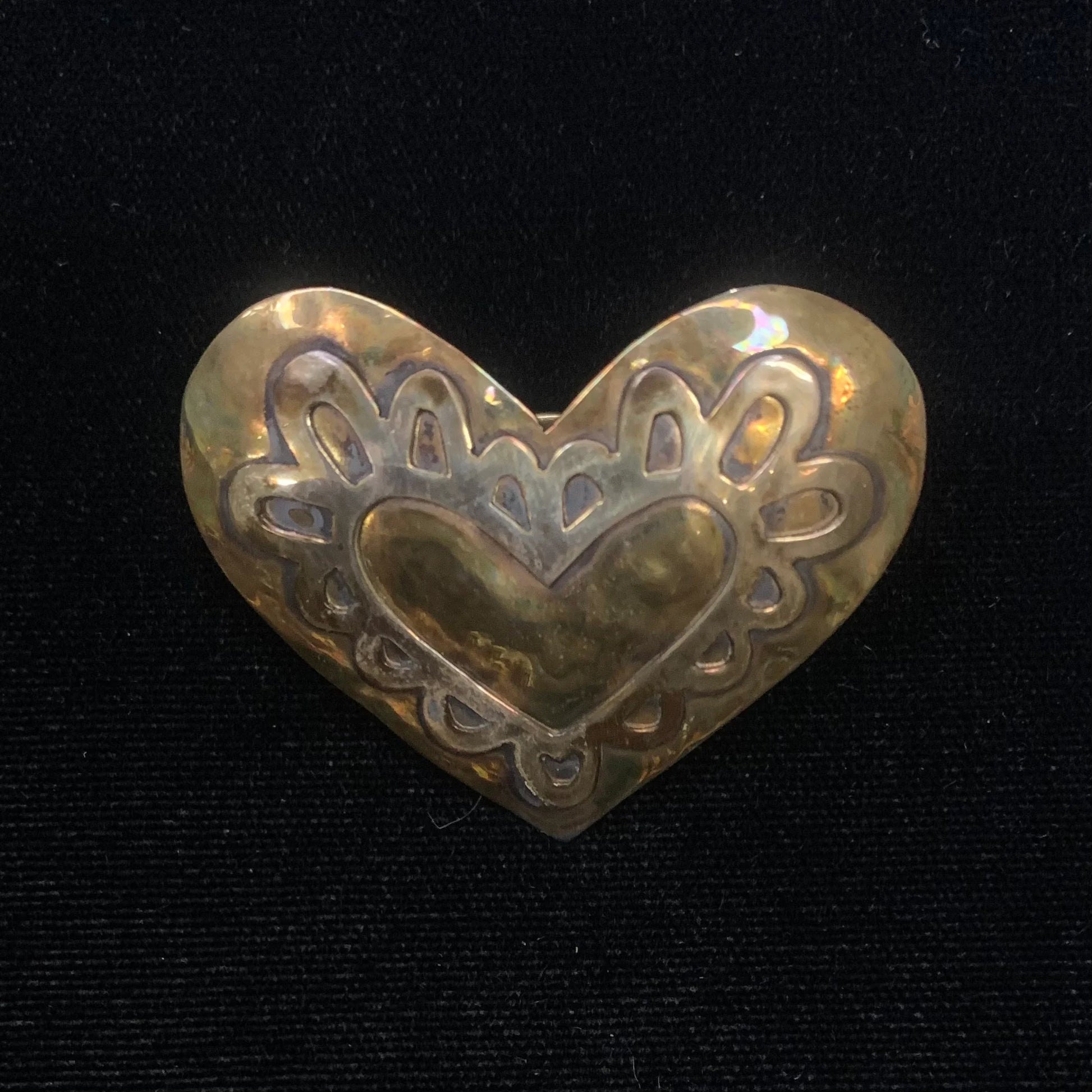 Decorative heart-shaped scarf tie with intricate patterns on a black background