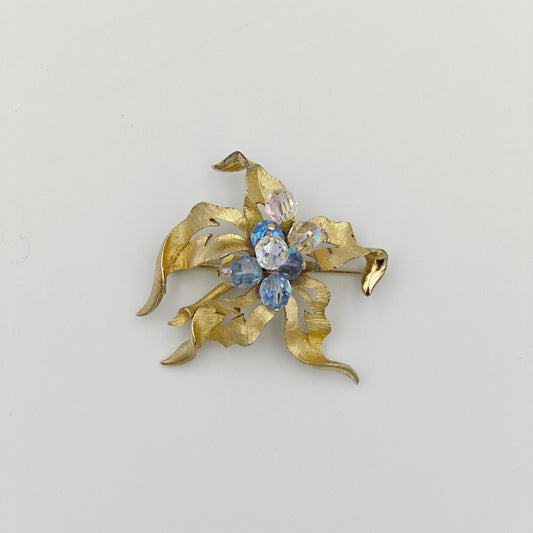 Gold brooch with blue gemstones on a light gray background