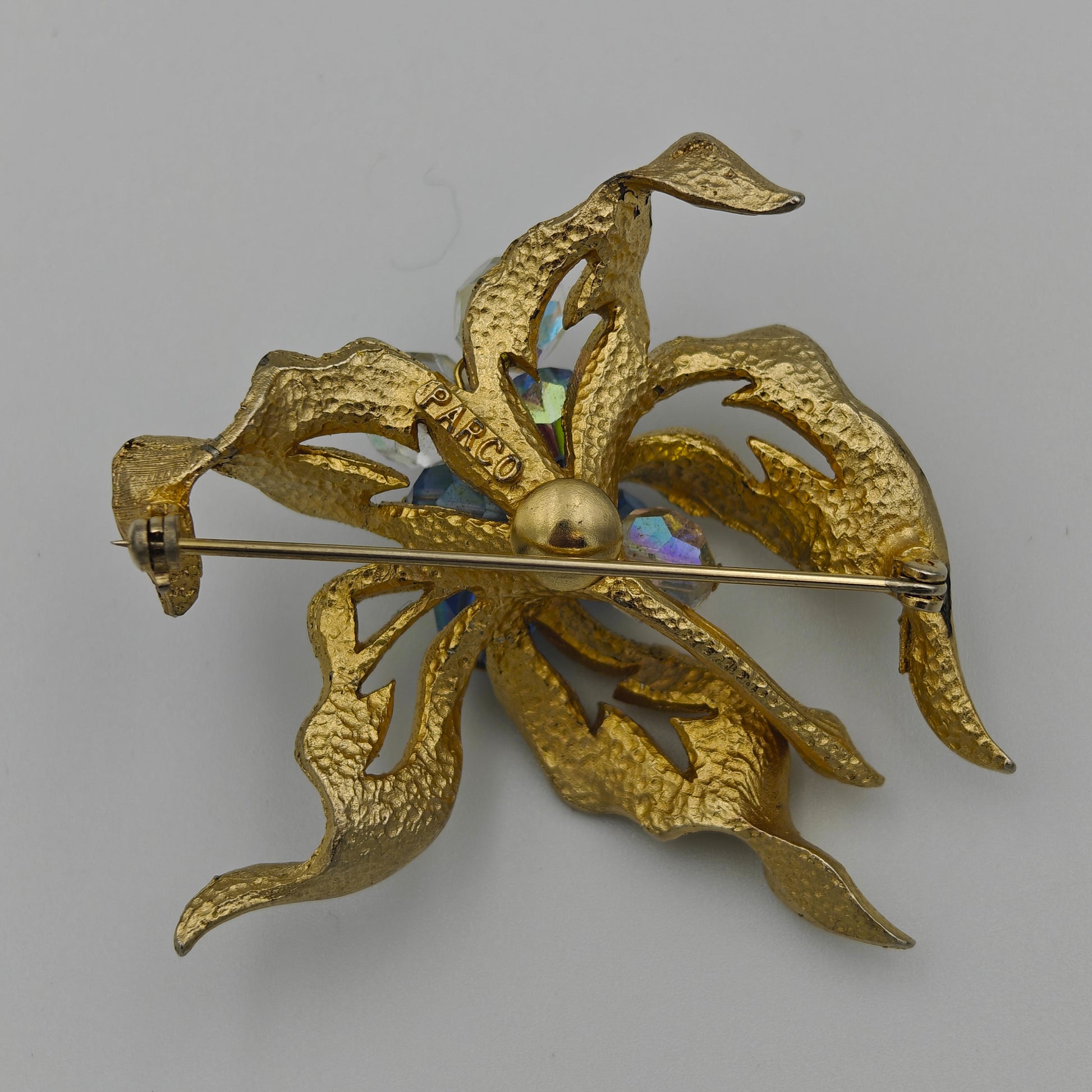 Gold brooch with intricate design on a gray background