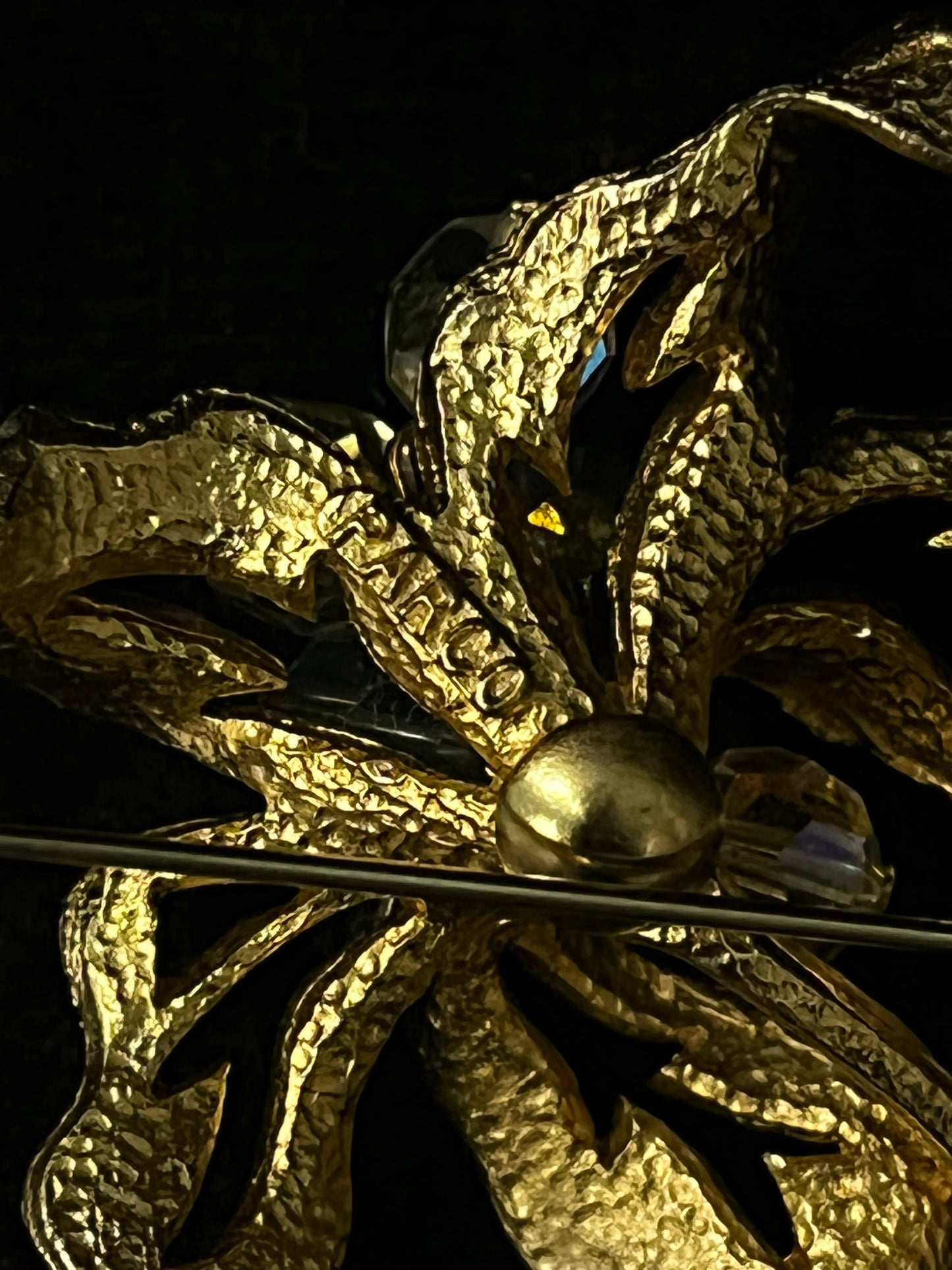 Close-up of a gold brooch with intricate design on a dark background