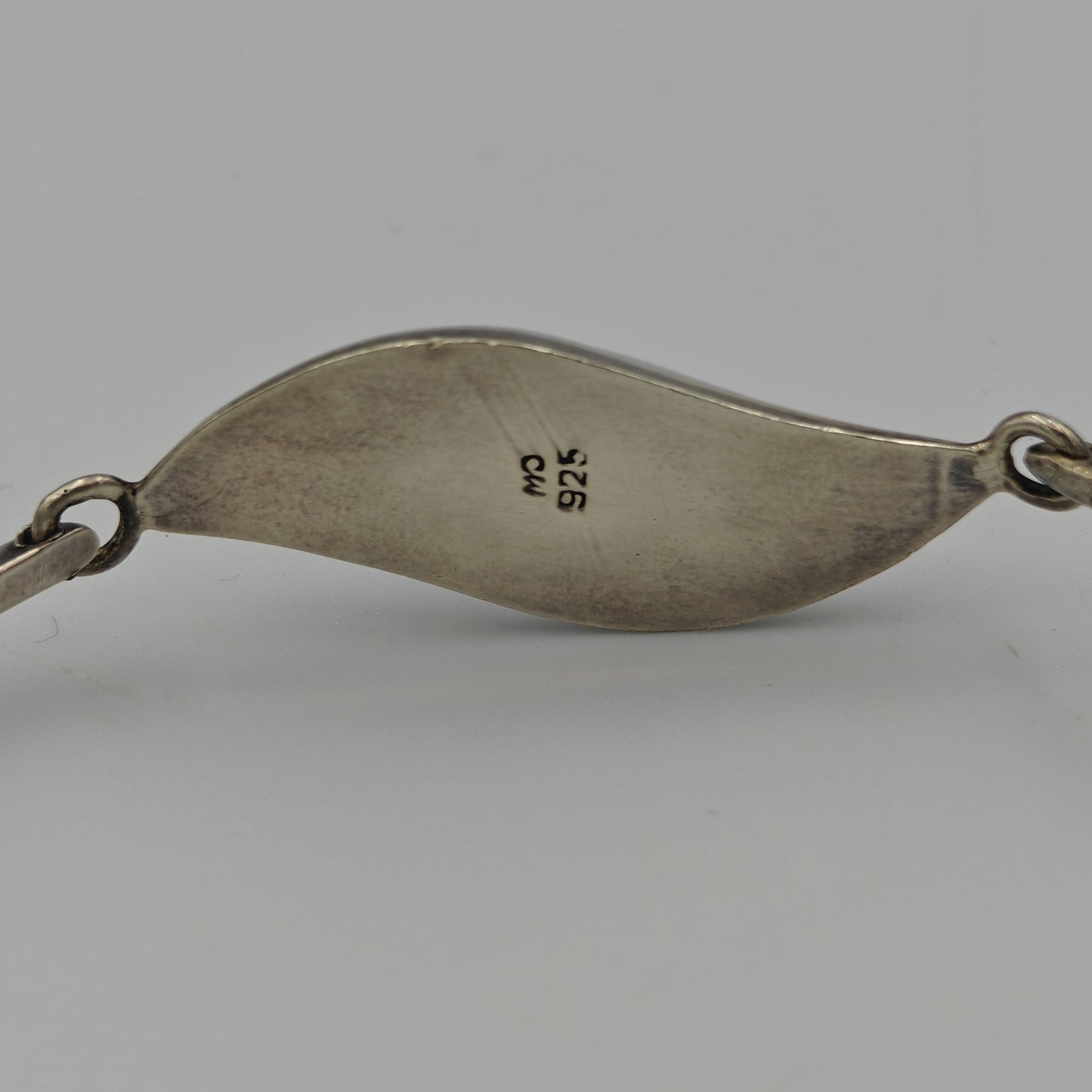 Back of silver bracelet with makers mark and 925 mark on a white background.
