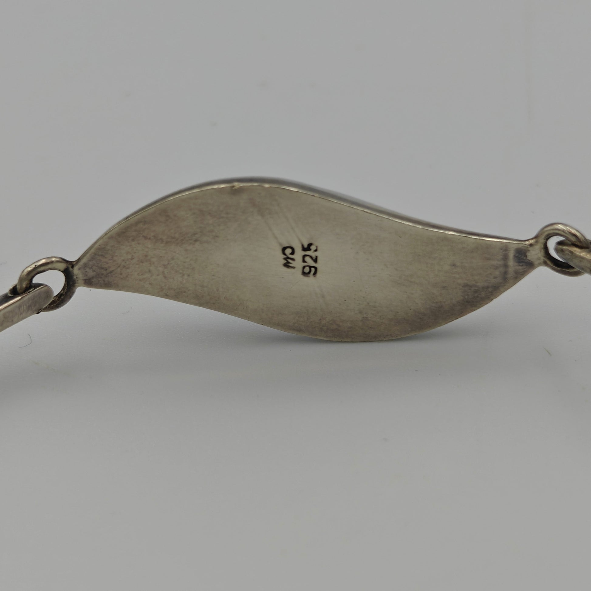 Back of silver bracelet with makers mark and 925 mark on a white background.