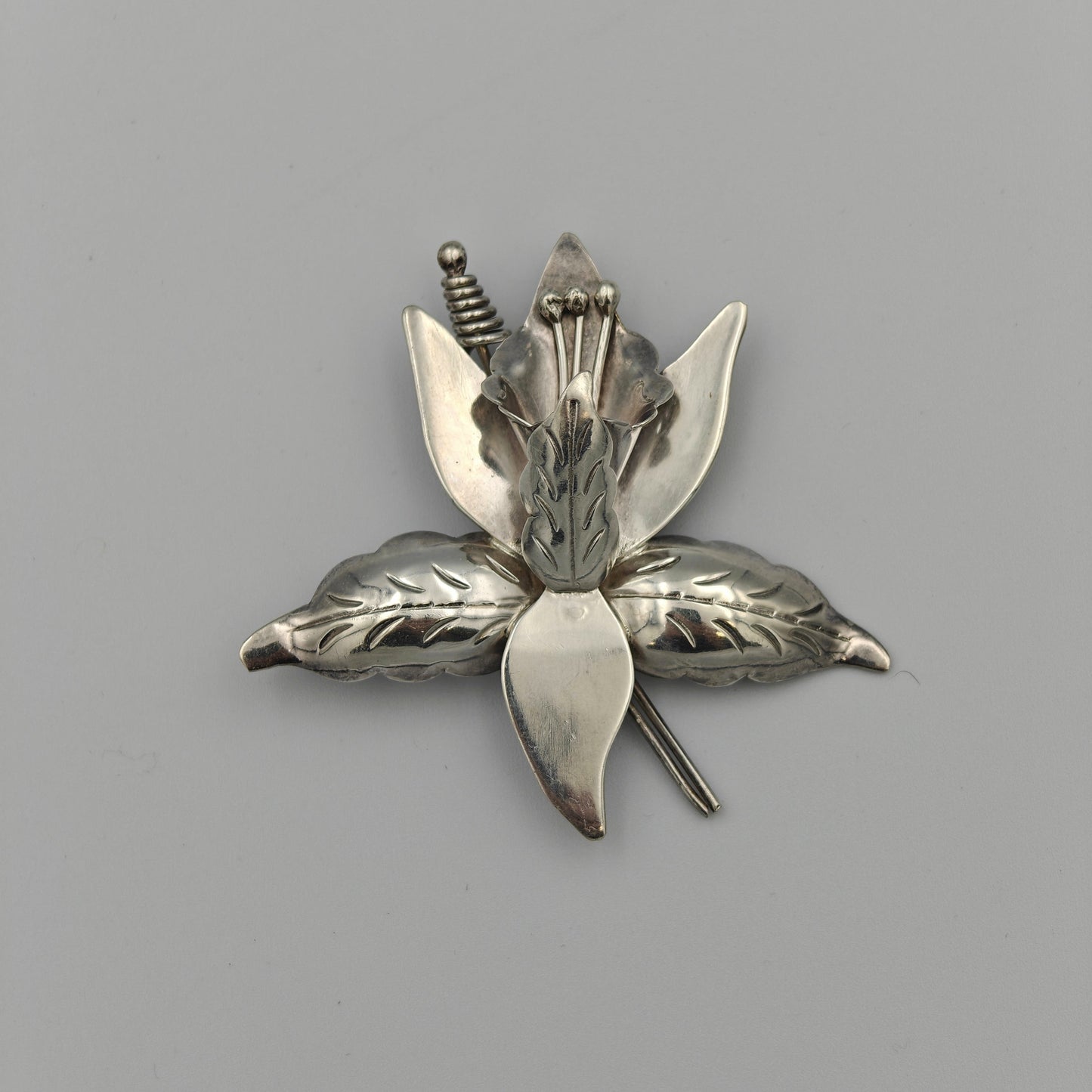 Silver brooch with floral design on a white background