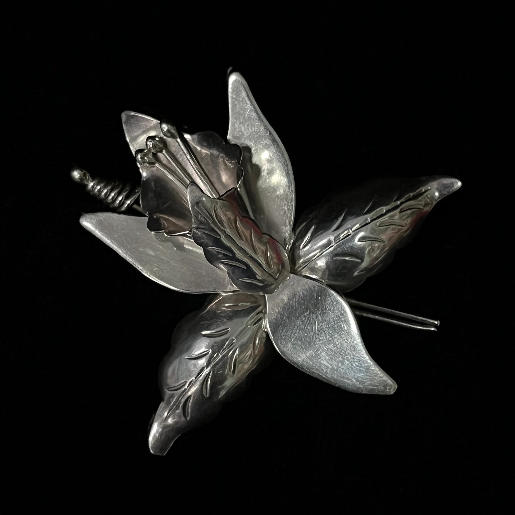 Silver flower-shaped brooch on a black background