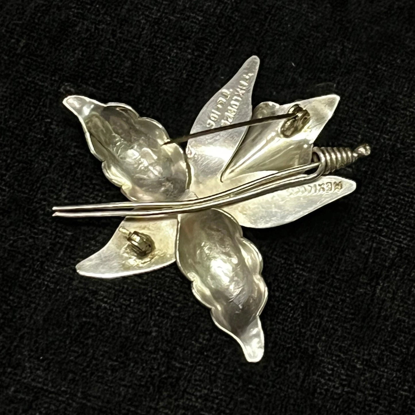Silver flower-shaped brooch on a black background