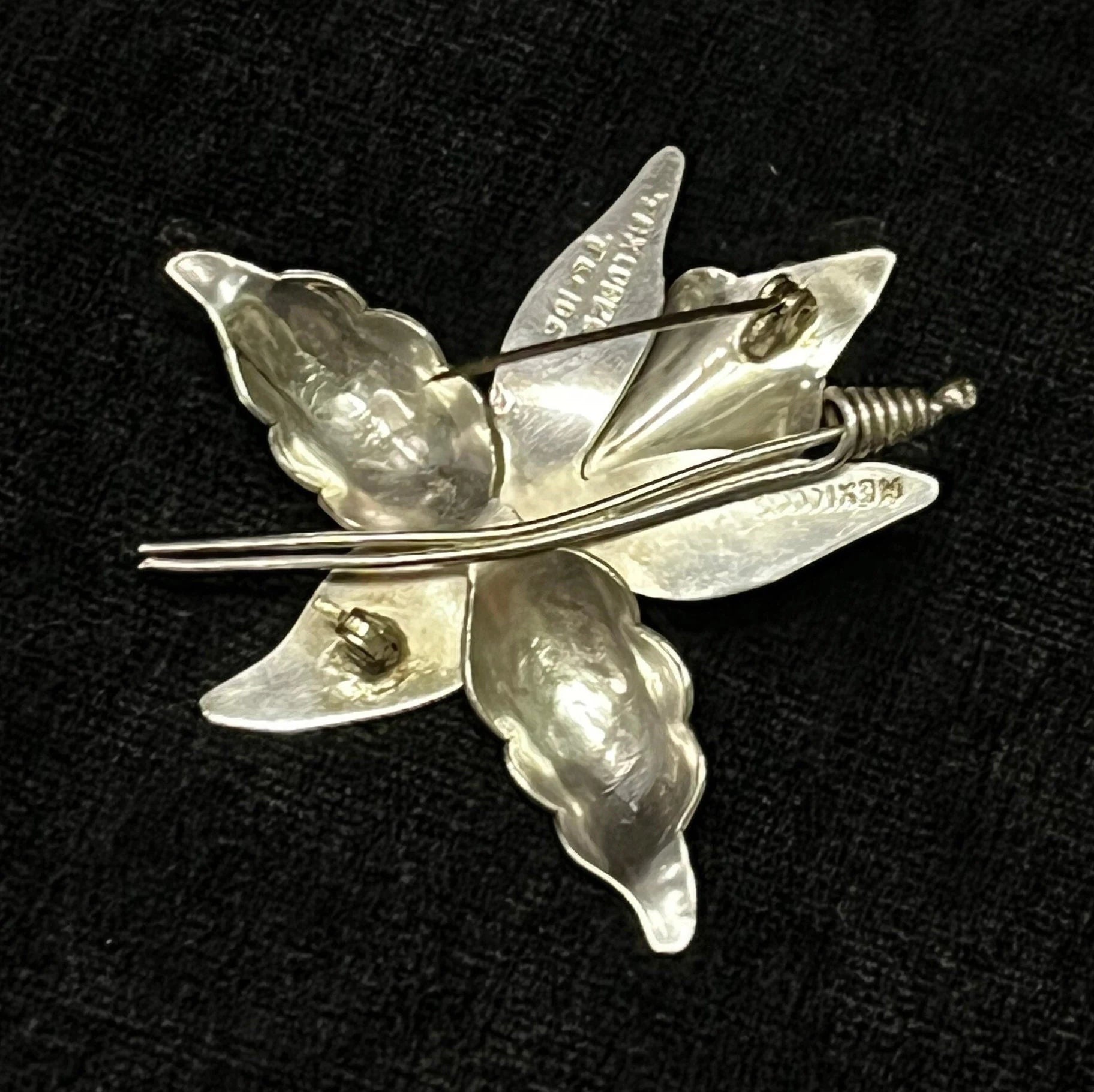 Silver flower-shaped brooch on a black background