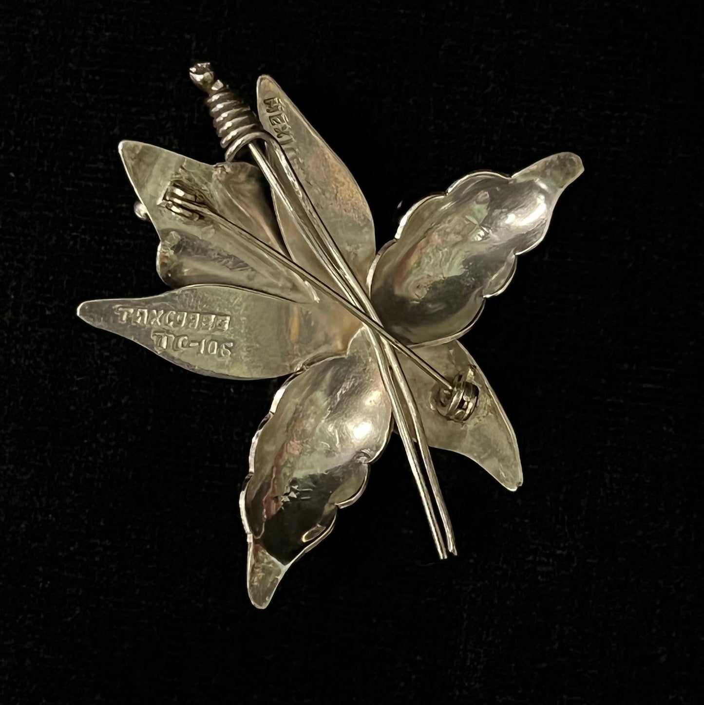 Silver flower-shaped brooch on a black background