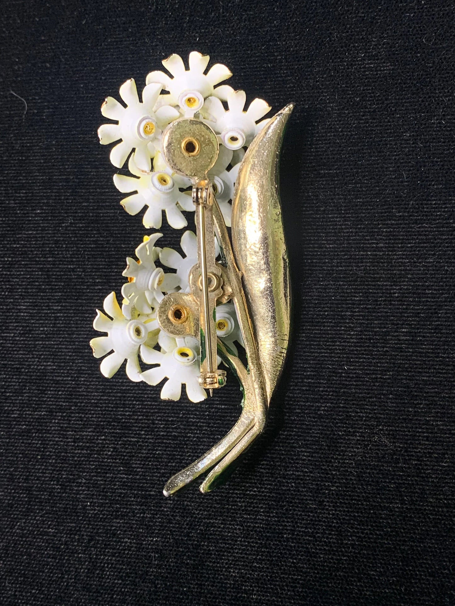 White brooch back with floral design on a black background
